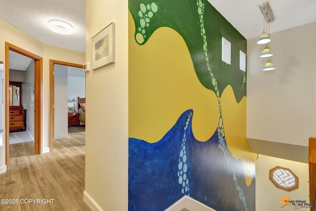 corridor with baseboards, a textured ceiling, and wood finished floors