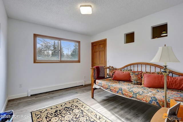 bedroom with baseboards, a textured ceiling, wood finished floors, and a baseboard radiator