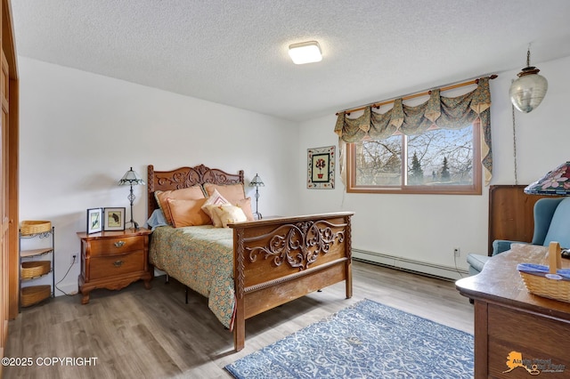bedroom with a textured ceiling, baseboard heating, and wood finished floors