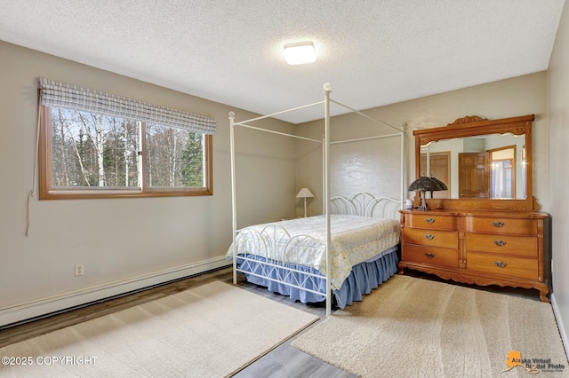 bedroom featuring a baseboard heating unit, a textured ceiling, and wood finished floors