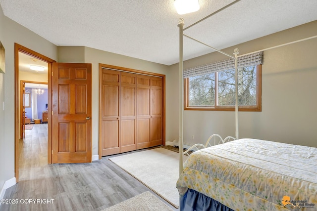 bedroom with light wood-style floors, baseboards, a closet, and a textured ceiling