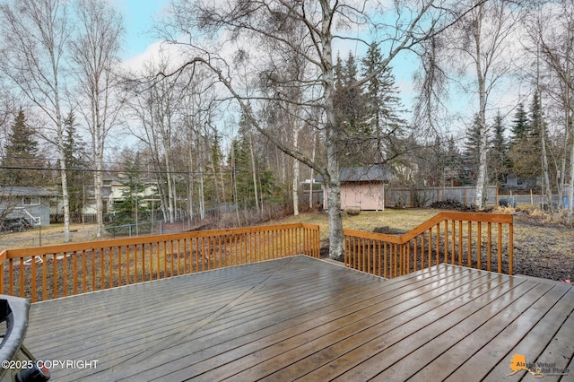wooden deck with an outbuilding, a fenced backyard, and a storage unit