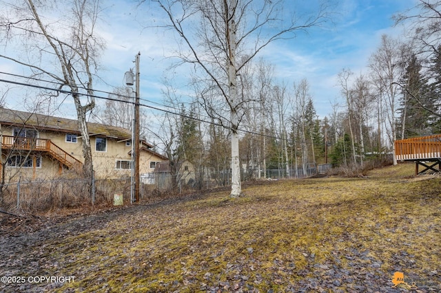 view of yard with fence, a wooden deck, and stairway