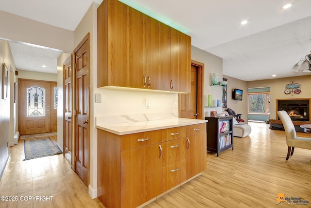 kitchen with light wood-style floors, brown cabinetry, recessed lighting, and open floor plan