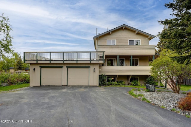 13120 Saunders Rd, Anchorage, AK 99516 - split level home featuring a garage, asphalt driveway, and a balcony