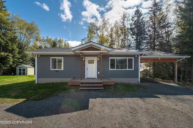 view of front of property featuring a storage unit, dirt driveway, an outdoor structure, a carport, and a front lawn