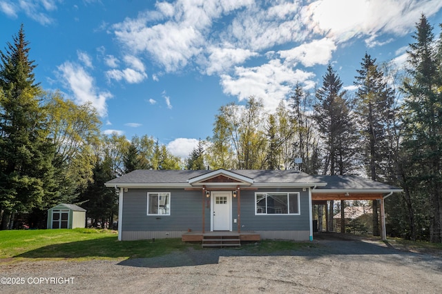 view of front of house with a shed, a carport, an outbuilding, dirt driveway, and a front yard