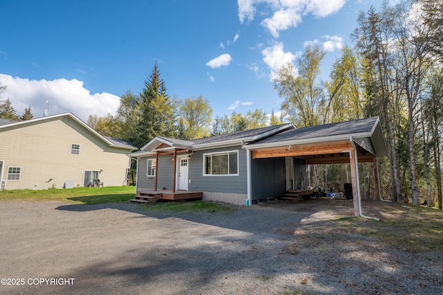 view of front facade with gravel driveway, a carport, and entry steps