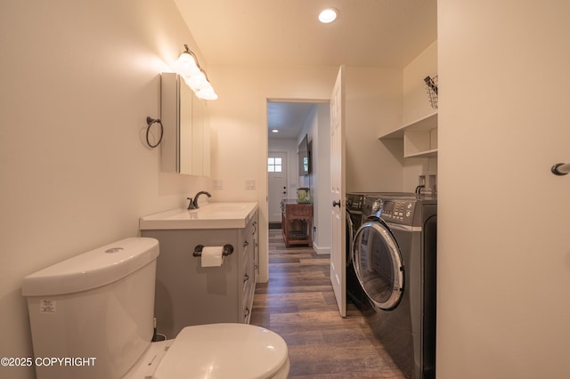 bathroom featuring washer / dryer, toilet, wood finished floors, vanity, and recessed lighting