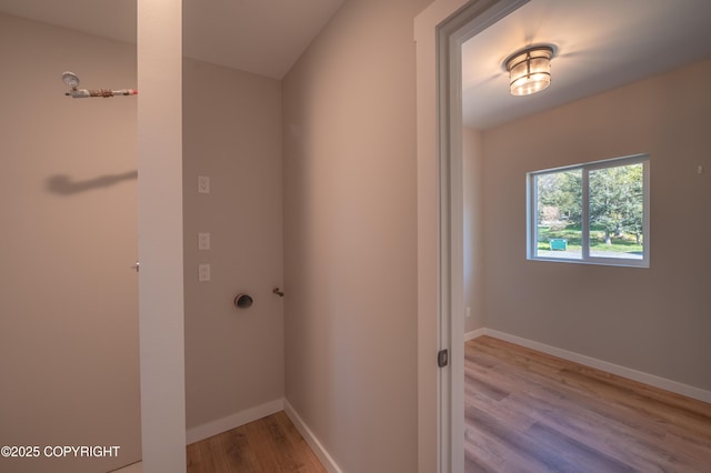clothes washing area with wood finished floors and baseboards