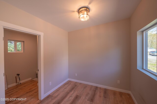 spare room featuring light wood-style floors, plenty of natural light, and baseboards