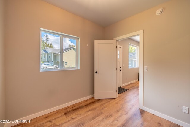 unfurnished room with baseboards, light wood-style flooring, and a smoke detector