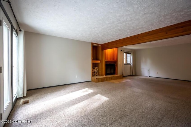 19532 Ostovia Cir, Eagle River, AK 99577 - unfurnished living room featuring a textured ceiling, carpet floors, a fireplace with raised hearth, visible vents, and beam ceiling