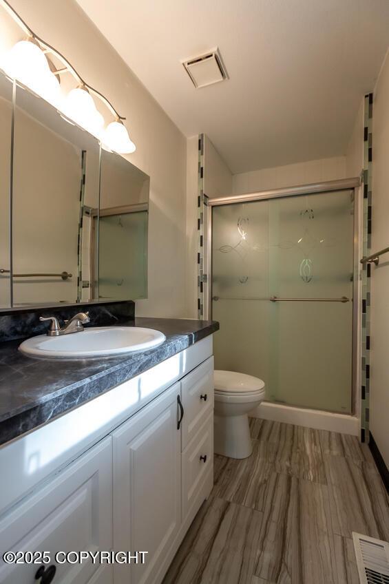 19532 Ostovia Cir, Eagle River, AK 99577 - bathroom featuring toilet, vanity, visible vents, and a stall shower