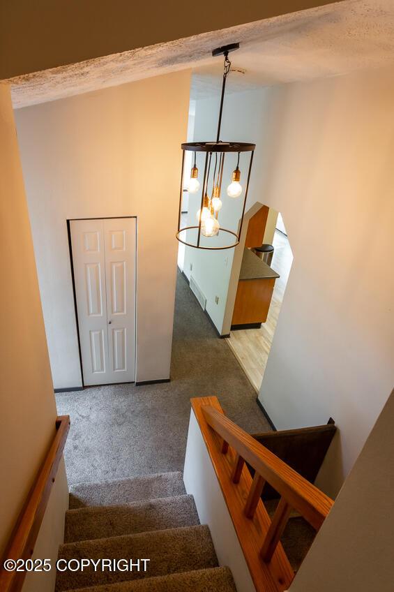 19532 Ostovia Cir, Eagle River, AK 99577 - staircase with a notable chandelier and carpet
