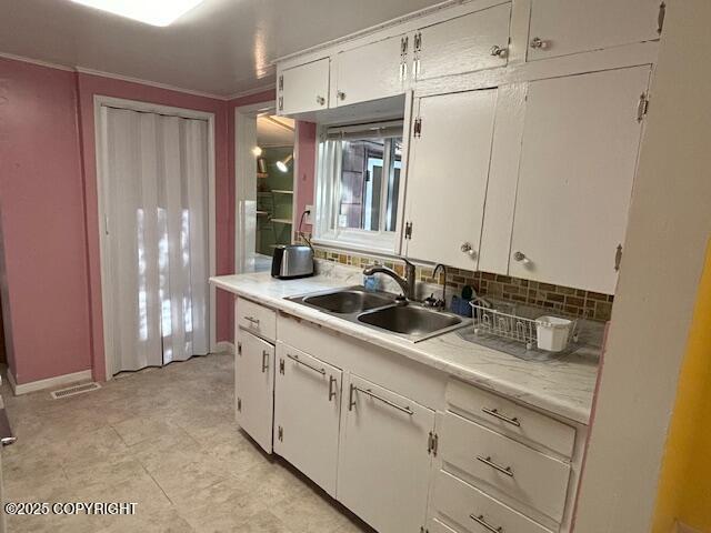 22539 Needles Loop, Chugiak, AK 99567 - kitchen featuring white cabinetry, light countertops, decorative backsplash, and a sink