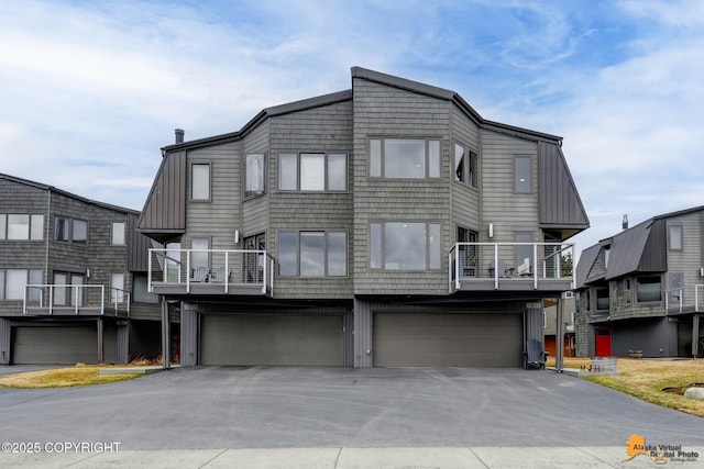 view of front of house with a garage, a balcony, and driveway
