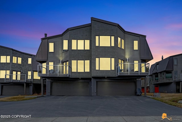 view of front of property featuring board and batten siding, an attached garage, concrete driveway, and a balcony