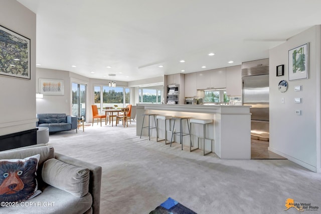 living area with recessed lighting and light colored carpet