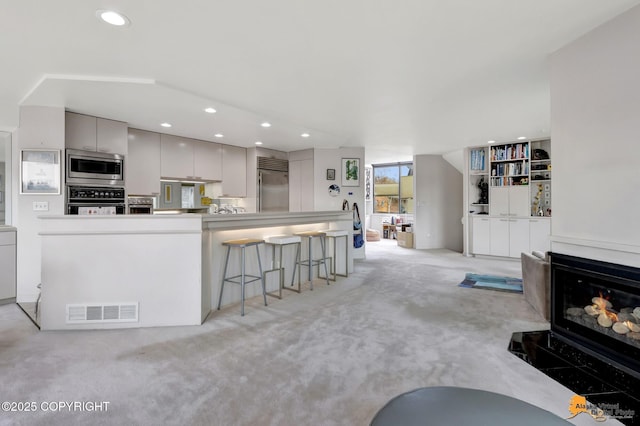 kitchen with visible vents, built in appliances, light colored carpet, recessed lighting, and gray cabinetry