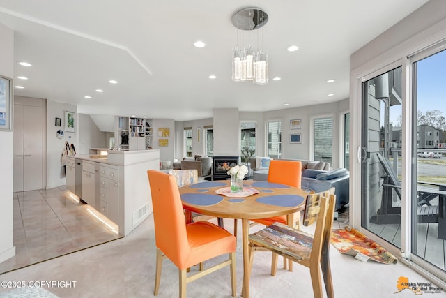 dining room featuring recessed lighting, a chandelier, and a lit fireplace