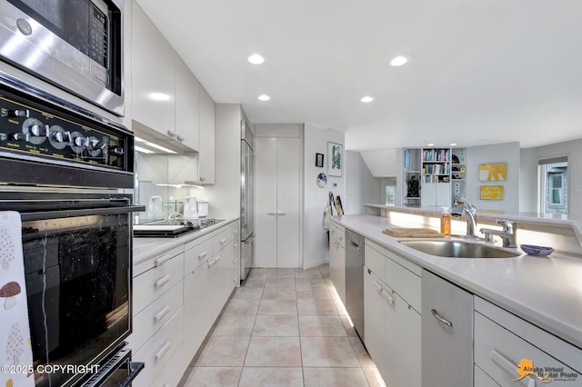 kitchen with light countertops, under cabinet range hood, white cabinets, a sink, and black appliances