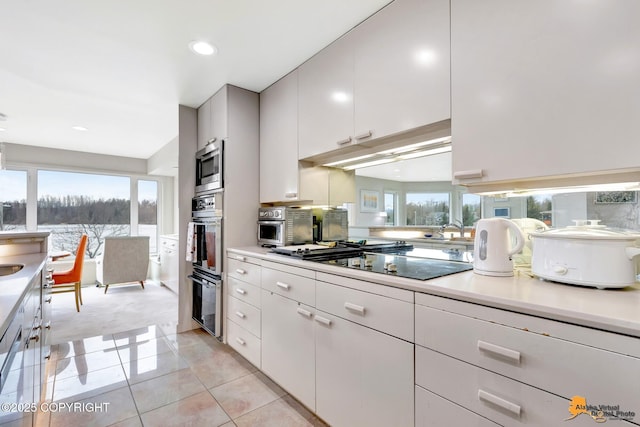 kitchen featuring light countertops, cooktop, stainless steel microwave, and light colored carpet
