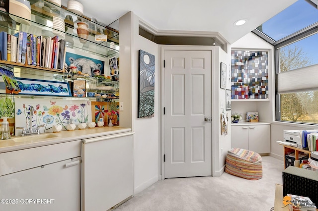 interior space with a sink, baseboards, recessed lighting, and light colored carpet