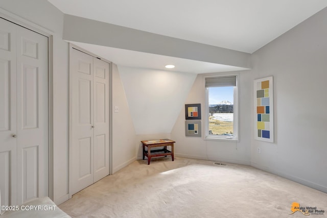 unfurnished bedroom featuring visible vents, baseboards, light colored carpet, and vaulted ceiling