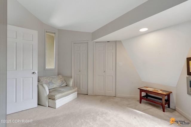 living area with carpet flooring, baseboards, and lofted ceiling