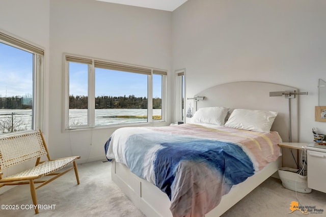 bedroom featuring light carpet, multiple windows, and a towering ceiling