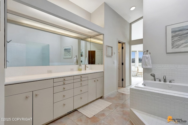 bathroom with a garden tub, tile patterned flooring, vanity, baseboards, and a high ceiling
