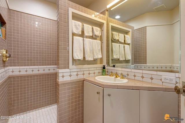 full bath with tile walls, visible vents, a tile shower, and vanity