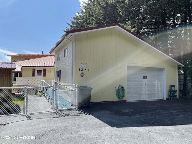 1221 W Kouskov St, Kodiak, AK 99615 - view of front facade with a gate, asphalt driveway, and a detached garage