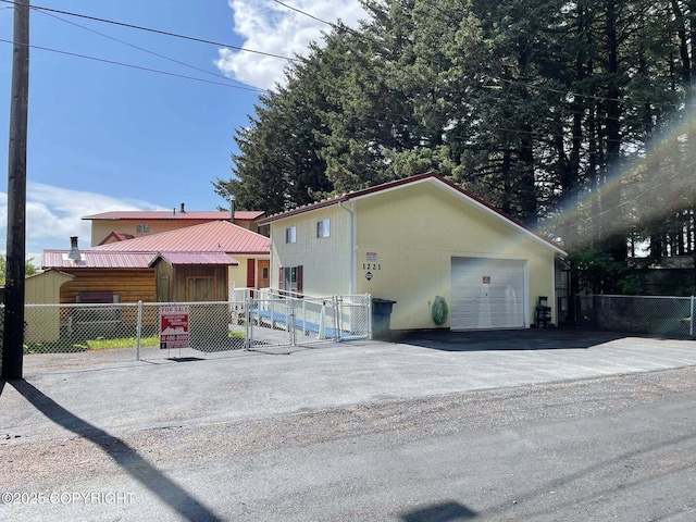 1221 W Kouskov St, Kodiak, AK 99615 - view of front of property featuring a fenced front yard, asphalt driveway, a garage, and a gate