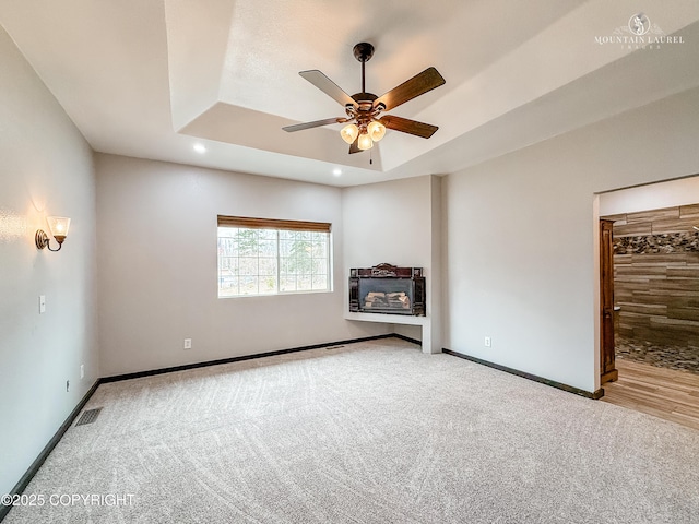 1340 N Rainbow Park Dr, Wasilla, AK 99623 - unfurnished living room featuring baseboards, carpet floors, a ceiling fan, and a raised ceiling