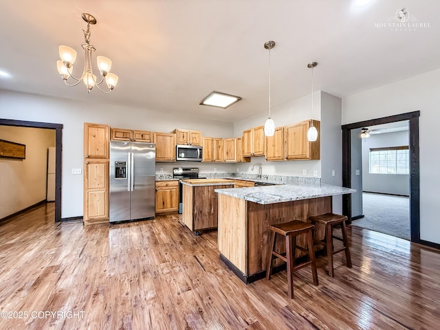 1340 N Rainbow Park Dr, Wasilla, AK 99623 - kitchen with a peninsula, baseboards, stainless steel appliances, and light wood-type flooring