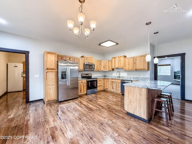 1340 N Rainbow Park Dr, Wasilla, AK 99623 - kitchen with light brown cabinetry, wood finished floors, a sink, a peninsula, and appliances with stainless steel finishes