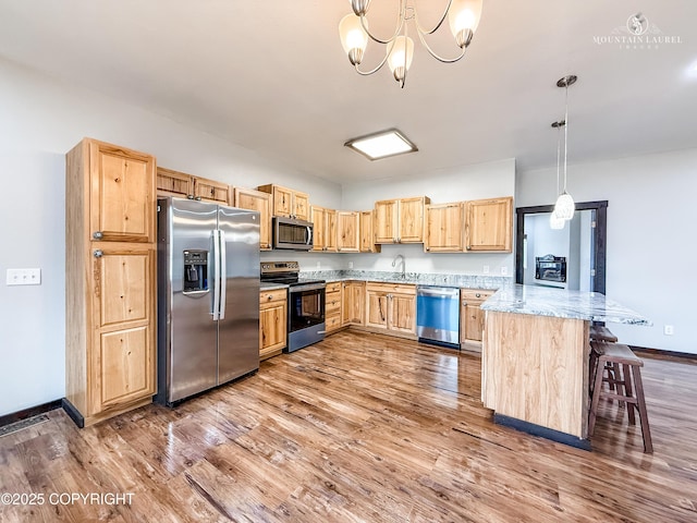 1340 N Rainbow Park Dr, Wasilla, AK 99623 - kitchen with light brown cabinetry, stainless steel appliances, wood finished floors, a sink, and a peninsula
