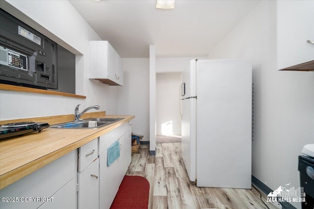 906 W 29th Pl, Anchorage, AK 99503 - kitchen with a sink, light countertops, white cabinets, freestanding refrigerator, and light wood-style flooring