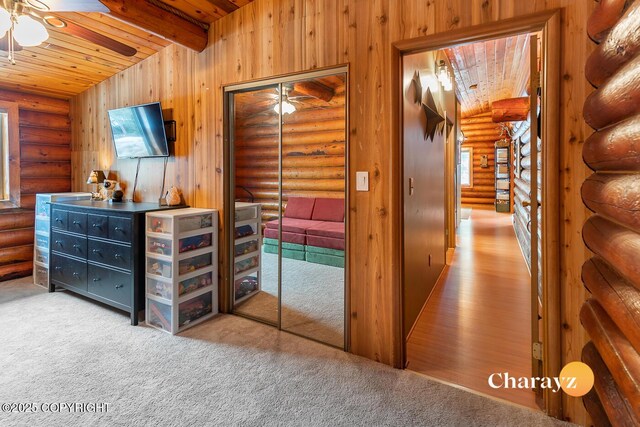 interior space with carpet flooring, log walls, multiple windows, and wooden ceiling