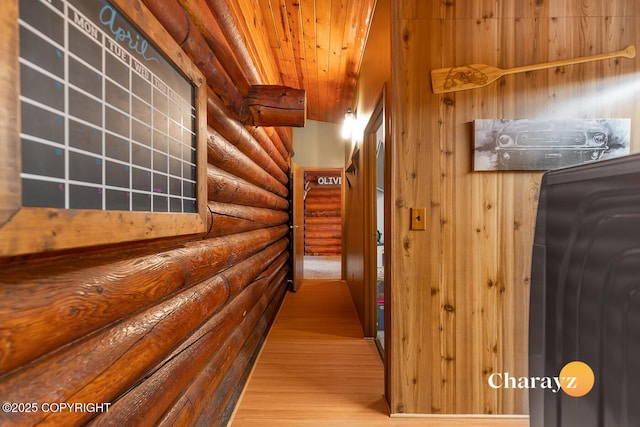corridor with log walls, wooden ceiling, and wood finished floors