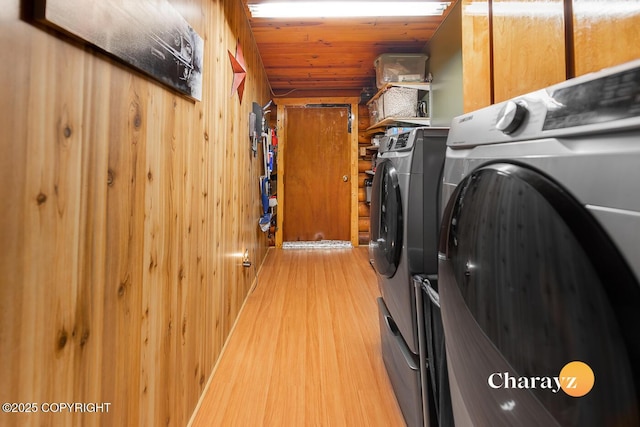 laundry area with washer and dryer, wood finished floors, wood walls, and cabinet space