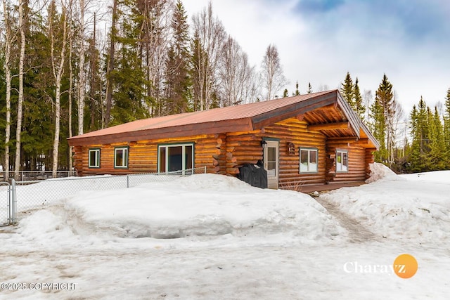 exterior space featuring log siding, metal roof, and fence