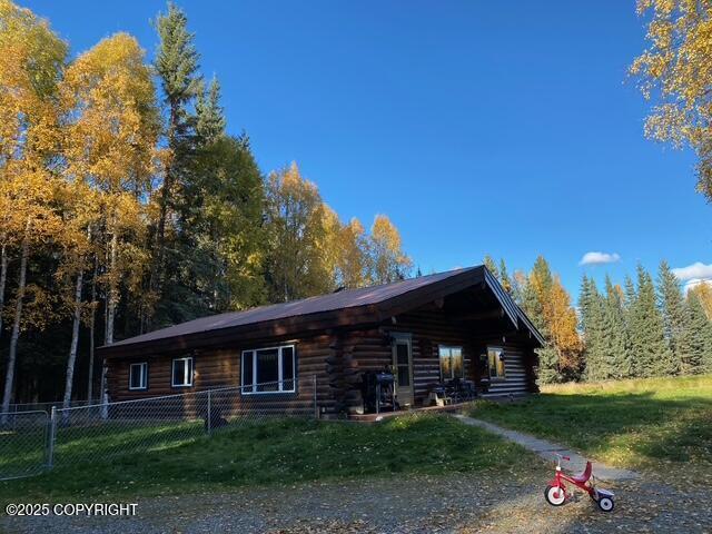 view of front of property with log siding, fence, and a front lawn