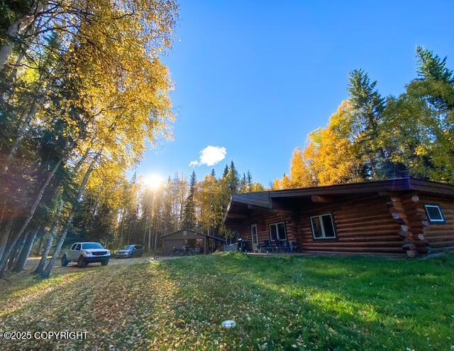 view of side of property with log exterior and a lawn