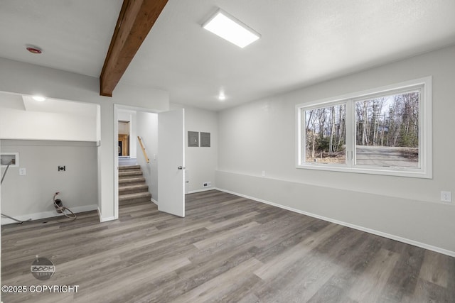 below grade area featuring baseboards, wood finished floors, and stairs