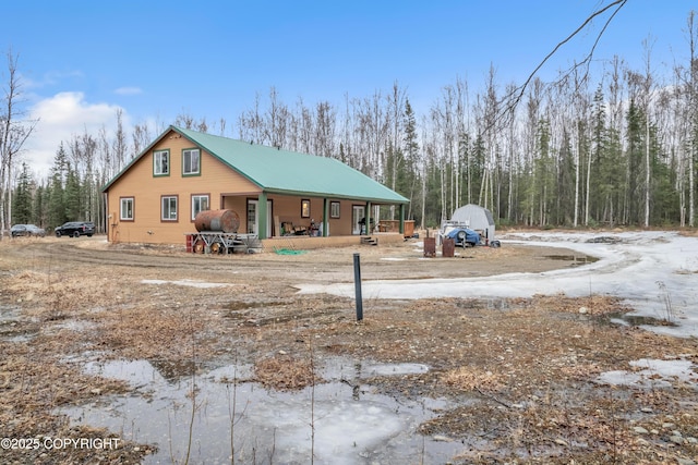 rear view of property with metal roof and covered porch