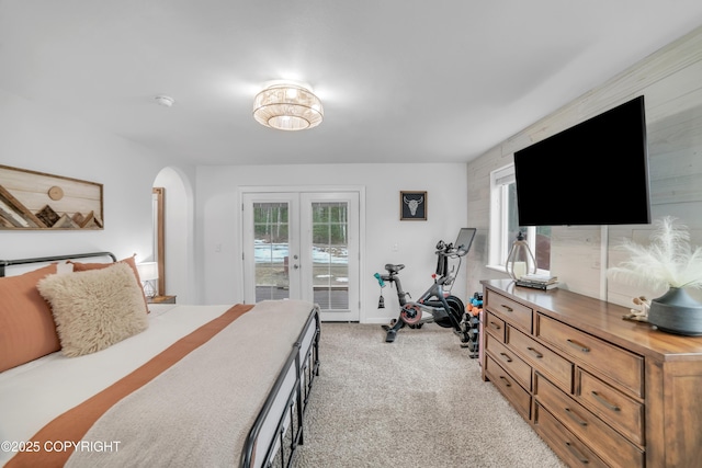 bedroom with arched walkways, light colored carpet, access to outside, and french doors