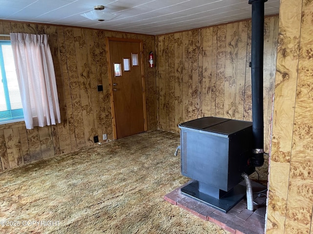 entrance foyer featuring carpet floors, a wood stove, and wooden walls